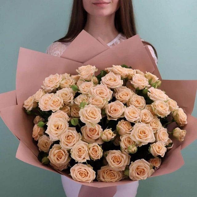 Букет из кремовых кустовых роз вблизи в руках
